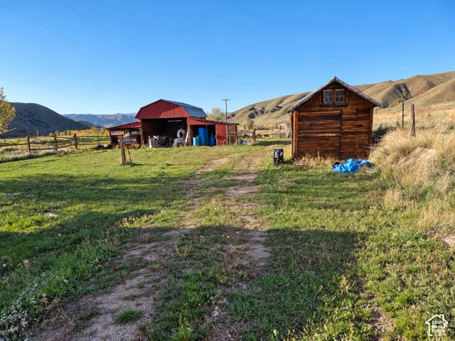Expansive acreage featuring a red-painted barn, a log-style storage structure, and mountain topography