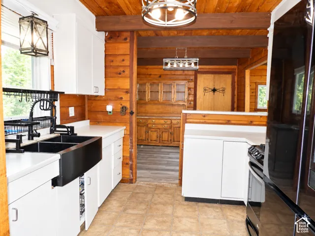 Kitchen featuring white cabinetry, black apron-front sink, exposed wood beams, and built-in wood hutch