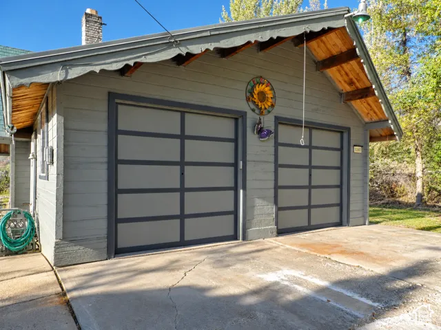 Detached two-car garage featuring horizontal lap siding, a gable roof with exposed wood soffits, and dual multi-panel garage doors