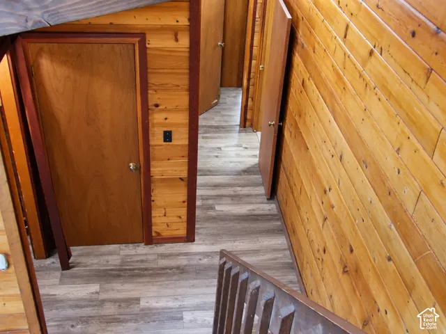 Interior hallway featuring horizontal wood paneling, wood-finish flooring, and solid wood interior doors