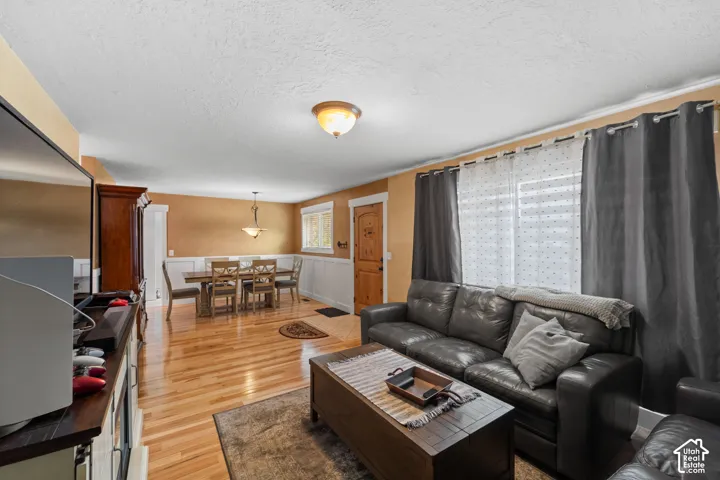 Wood-finish flooring, white wainscoting, a flush-mount ceiling light fixture, a pendant light fixture, and a natural wood entry door