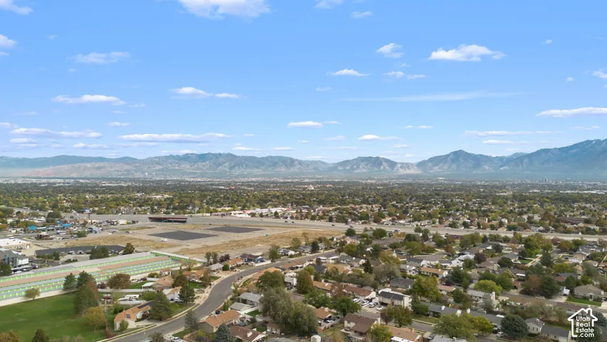 Aerial perspective featuring an expansive mountain backdrop and mature tree canopy throughout the surrounding residential area