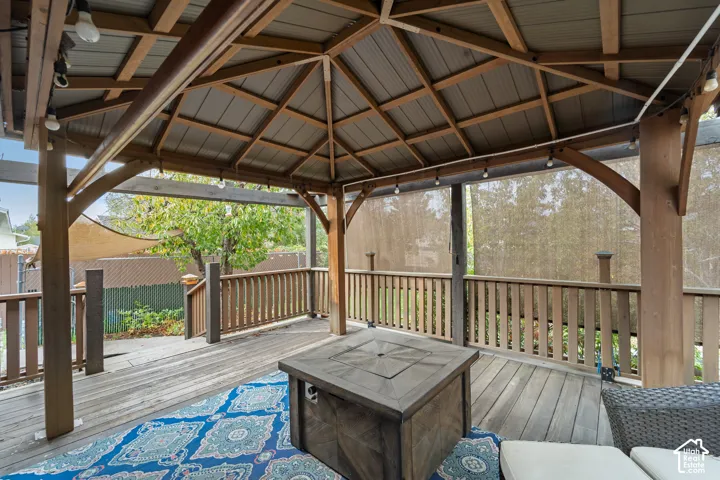 Covered wood gazebo featuring a timber-frame structure, plank wood decking, and built-in railing