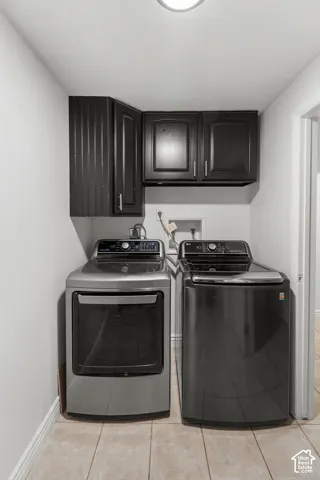 Laundry space featuring wall-mounted dark cabinetry and tile flooring
