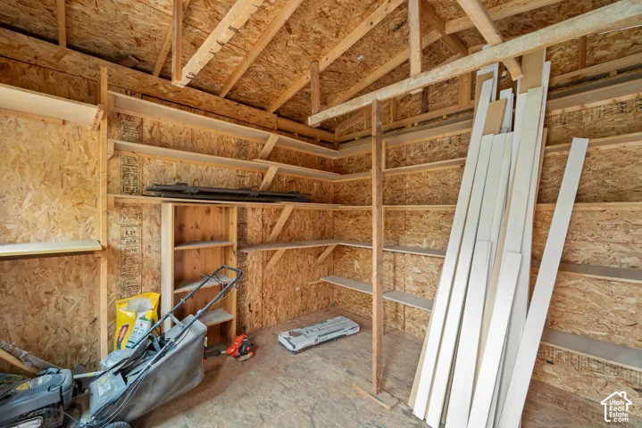 Storage structure featuring exposed wood-stud framing, oriented strand board (OSB) interior walls, and multiple levels of built-in wooden shelving