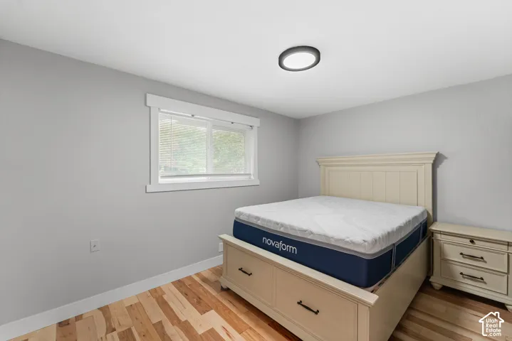 Neutral-toned interior space featuring wood-finish flooring, a horizontal slider window with crisp white casing, and a flush-mount circular LED light fixture