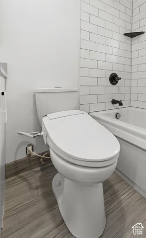 Bathroom featuring white subway tile tub surround, matte black plumbing fixtures, built-in corner shelf, and wood-finish flooring