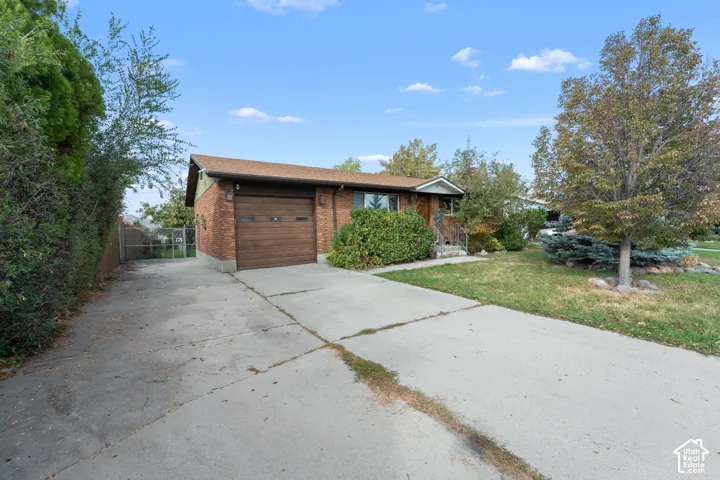 Brick exterior featuring a single-car garage, concrete driveway, and established landscaping