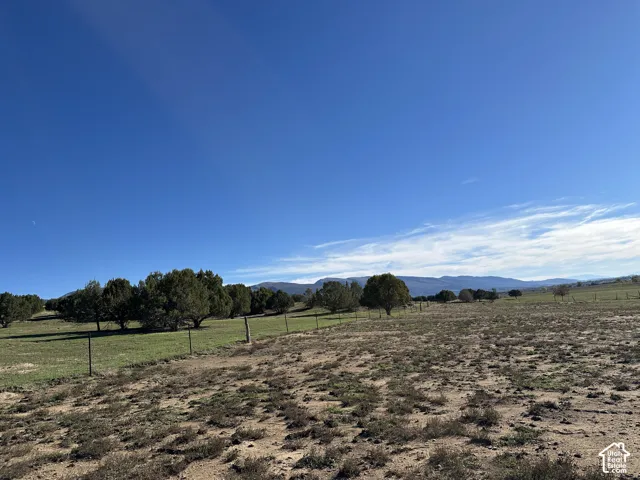 Expansive acreage featuring wire perimeter fencing, native vegetation, mature trees, and a mountain backdrop