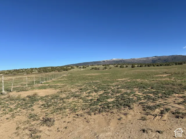 Expansive acreage featuring wire fencing, native ground cover, and prominent mountain scenery