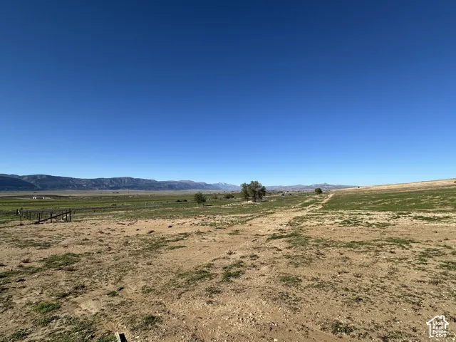 Expansive open terrain featuring native vegetation, a perimeter wire fence, and mountain scenery