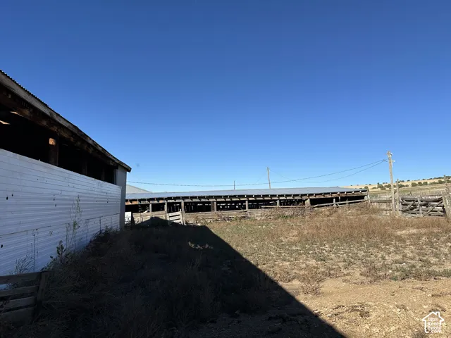 Agricultural property featuring metal-sided structures, open-air barn buildings with corrugated metal roofing, and fenced outdoor space