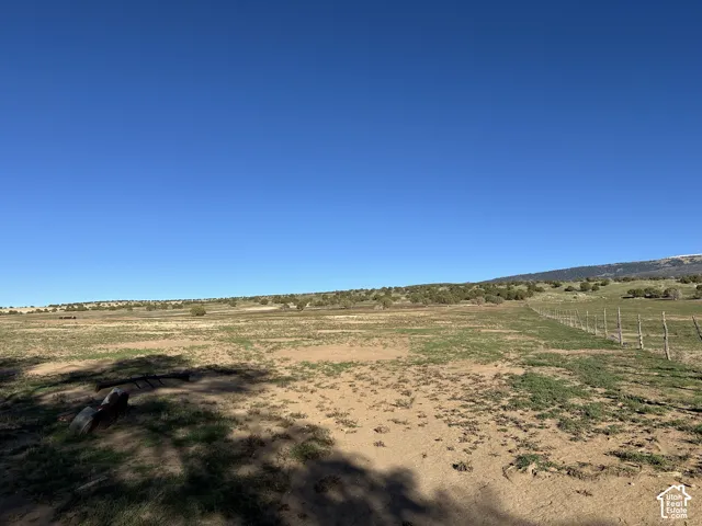 Expansive acreage featuring native terrain, peripheral wire fencing, and mountain topography