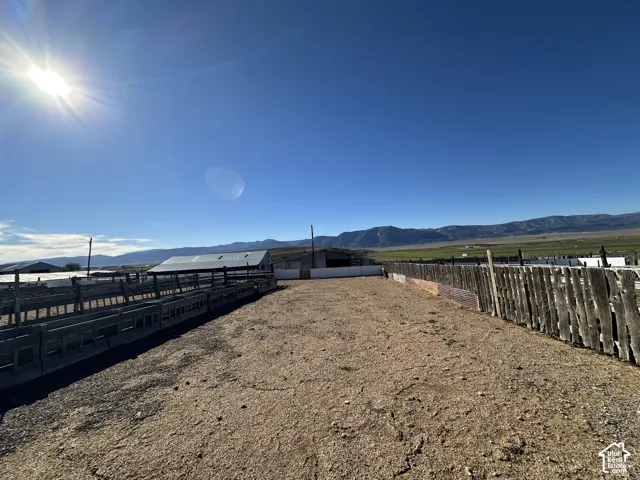 Expansive fenced enclosures featuring extensive wooden corrals and metal-roofed structures set against a prominent mountain backdrop