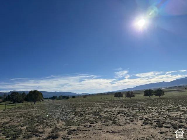 Expansive acreage featuring wire fencing, mature trees, and mountain terrain