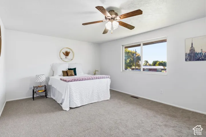 Neutral wall tones, wall-to-wall carpeting, ceiling fan with multi-light fixture, and horizontal slider window