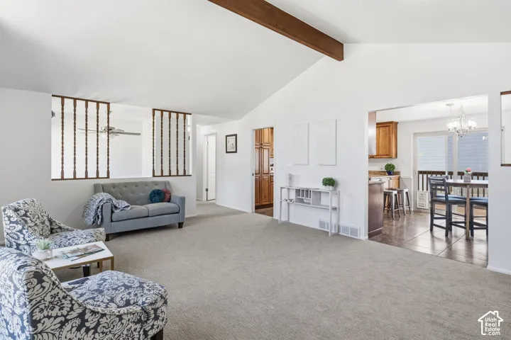 Vaulted ceiling with exposed wood-finish structural beam, decorative wood spindle room divider, and wall-to-wall carpeting