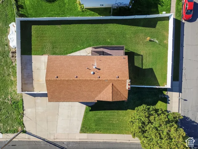 Aerial perspective of a property featuring a fenced-in rear yard, concrete driveway, and elevated rear deck
