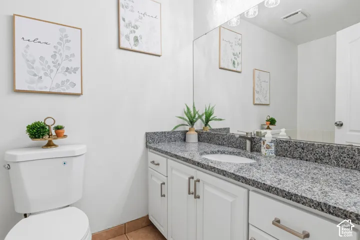 White vanity cabinetry featuring brushed nickel hardware, stone-composite countertop, oval undermount sink, and full-width wall mirror