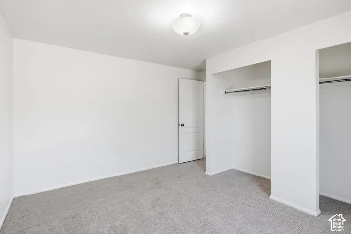 Room featuring neutral-toned carpeting, two built-in reach-in closets with metal shelving, a white paneled interior door, and a centered flush-mount ceiling light fixture