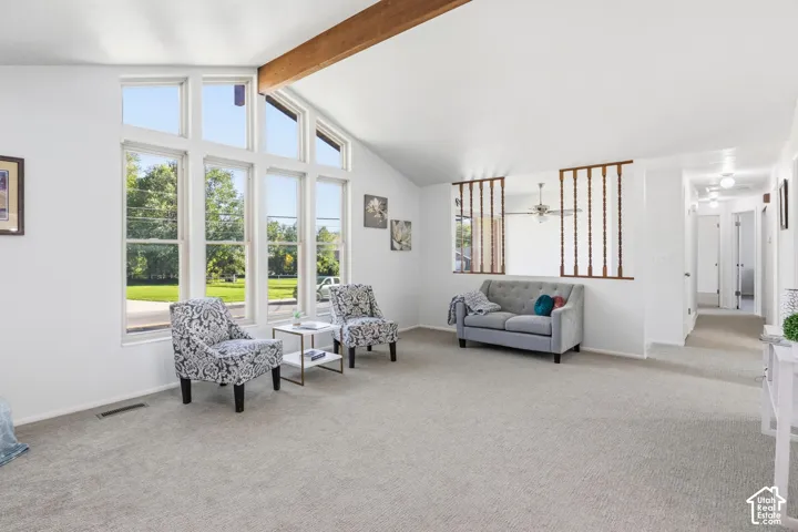 Vaulted ceiling with exposed structural beam, floor-to-ceiling multi-pane windows, and decorative wood spindle partition