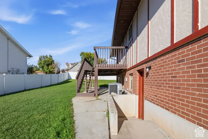 Exterior brick and stucco facade, raised wooden deck with staircase, concrete patio, and enclosed backyard with vinyl privacy fencing