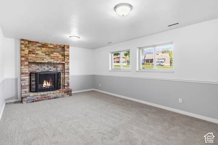 Multi-tone brick fireplace, neutral carpeting, dual sliding windows, and decorative chair rail molding