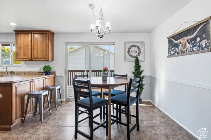 Kitchen featuring wood cabinetry, stone-finish countertops, a multi-light chandelier, tile flooring, and sliding glass doors