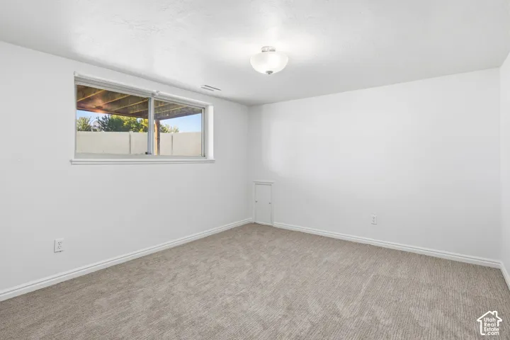 Neutral-toned carpeting, white walls, flush-mount ceiling lighting, and a horizontal sliding window