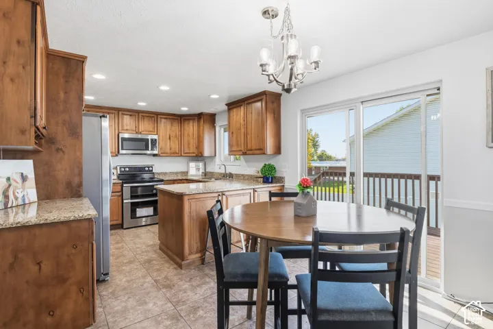 Kitchen featuring wood cabinetry, stone-surface countertops, tile flooring, stainless steel appliances, and sliding glass doors