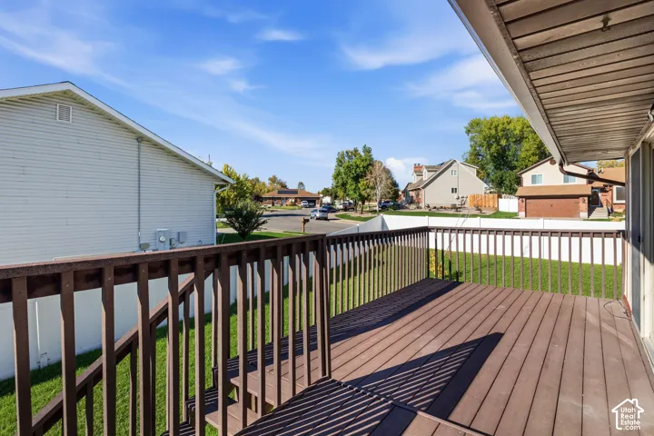Elevated wooden deck with vertical balustrades, stairs, and white vinyl perimeter fencing enclosing the lawn