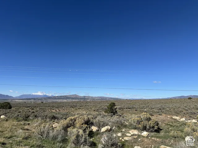 Expansive lot featuring high-desert terrain with native sagebrush, scattered rock outcroppings, and a backdrop of distant, snow-capped mountains