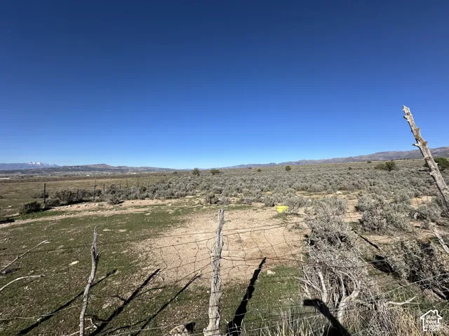 Expansive acreage featuring natural desert vegetation, perimeter wire fencing, and distant mountain backdrops