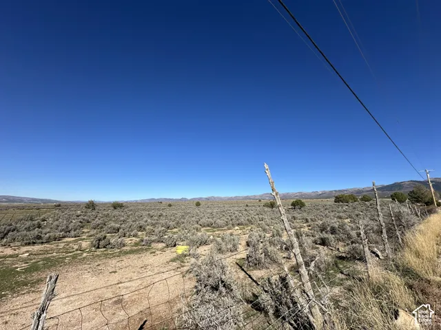 Expansive acreage featuring native desert vegetation and mountain backdrop with perimeter wire fencing