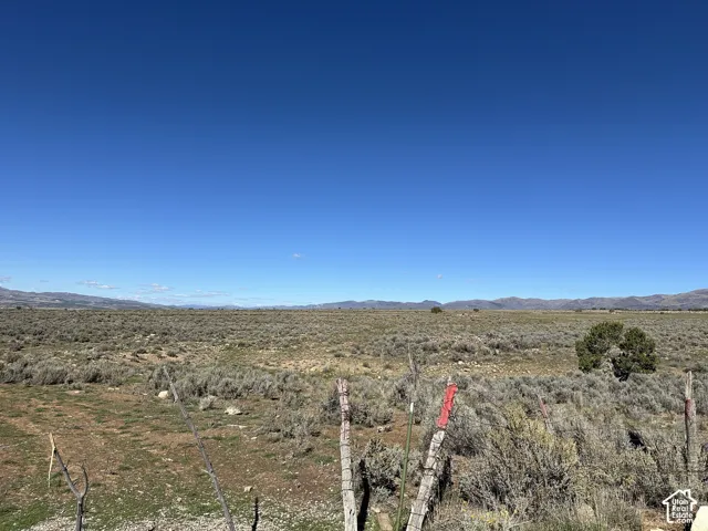Expansive lot featuring native desert landscaping, rugged terrain, and mountain silhouettes against a clear horizon