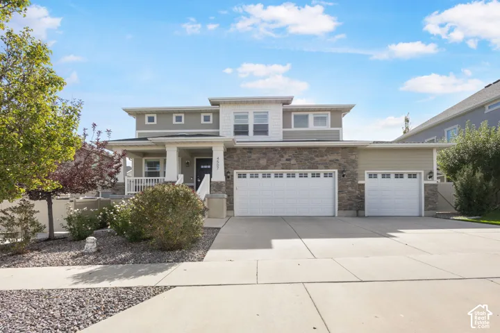 Two-story exterior featuring stone veneer accents, lap siding, a covered front porch, and a three-car garage
