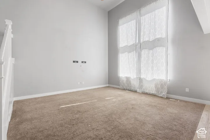 Vaulted ceilings, tall windows with vertical orientation, neutral wall color, and white staircase railing