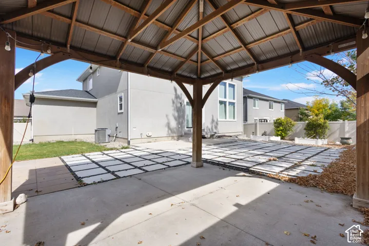 Outdoor pavilion featuring a timber-frame structure with a metal roof, concrete patio, and decorative paver grid inlay