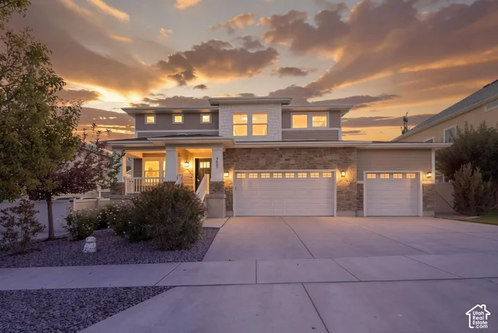 Two-story exterior featuring stone veneer accents, horizontal siding, a covered front porch with square columns, and a three-car garage
