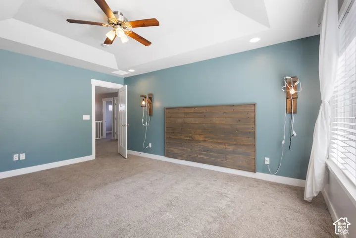 Tray ceiling featuring a central ceiling fan with integrated lighting and recessed lighting, wall-mounted wood accent paneling, and dual wooden light fixtures