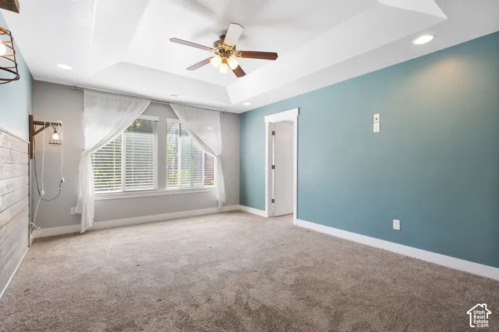 Tray ceiling with recessed lighting and a central ceiling fan, dual-tone wall finishes, and multi-pane windows