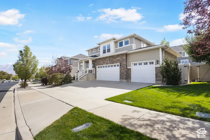 Two-story residence featuring horizontal lap siding, stone veneer masonry, a three-car garage, and concrete driveway