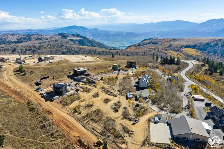 Aerial perspective of mountainous terrain featuring paved roadway access, expansive natural landscape, and integrated residential sites