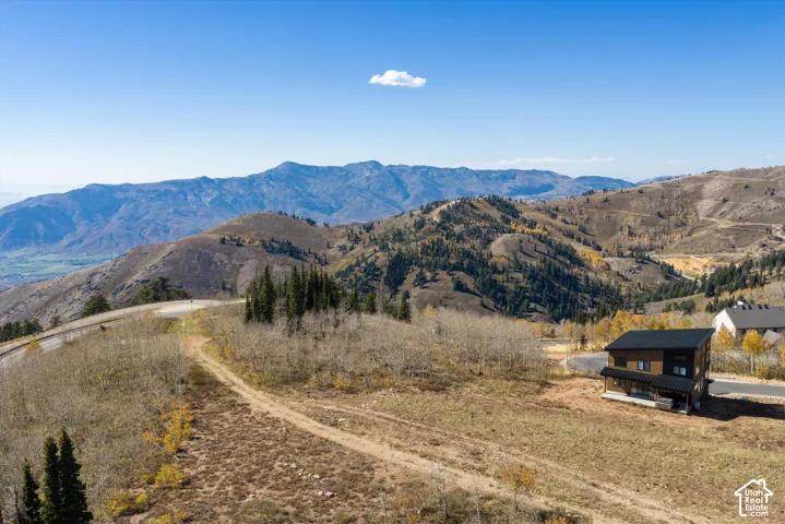 Multi-level exterior with dark metal roof, wood-finish siding, mountain backdrop, and expansive natural landscape