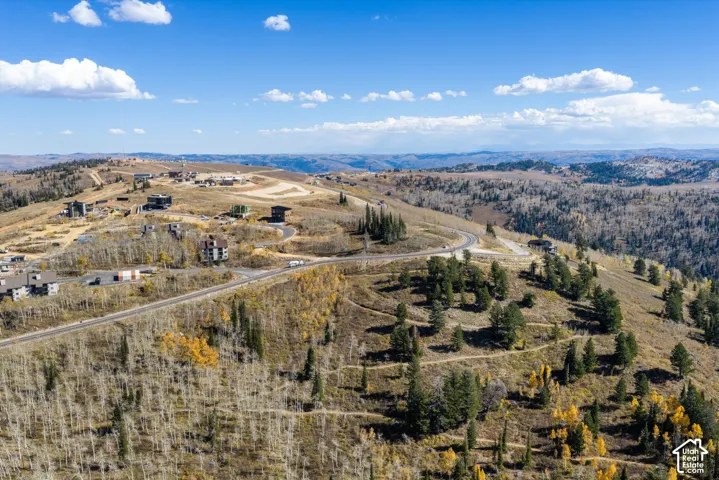 Aerial perspective showcasing expansive mountain terrain with established paved roadways and surrounding forest featuring aspen and coniferous trees
