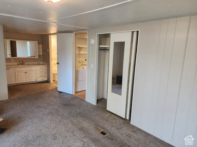 Built-in vanity featuring white cabinetry and a rectangular mirror, sliding closet doors with an integrated mirror, and laundry area with shelving