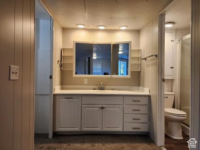 Bathroom vanity featuring white cabinetry, integrated countertop, tri-fold medicine cabinet with built-in side shelving, and recessed lighting