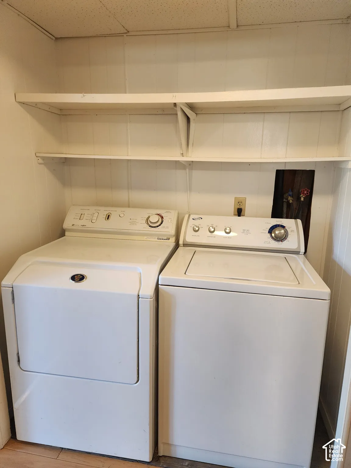 Laundry area featuring dual built-in shelving units and white vertical panel walls