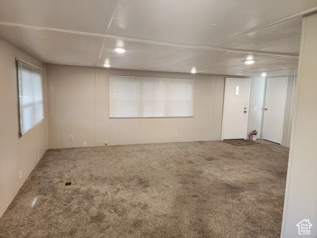 Interior space featuring recessed lighting, wall-to-wall carpeting, multiple windows with blinds, and a white entry door