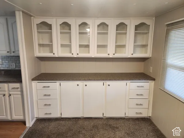 Built-in cabinetry featuring glass-front upper doors, white finish, stone-composite countertop, and integrated storage drawers